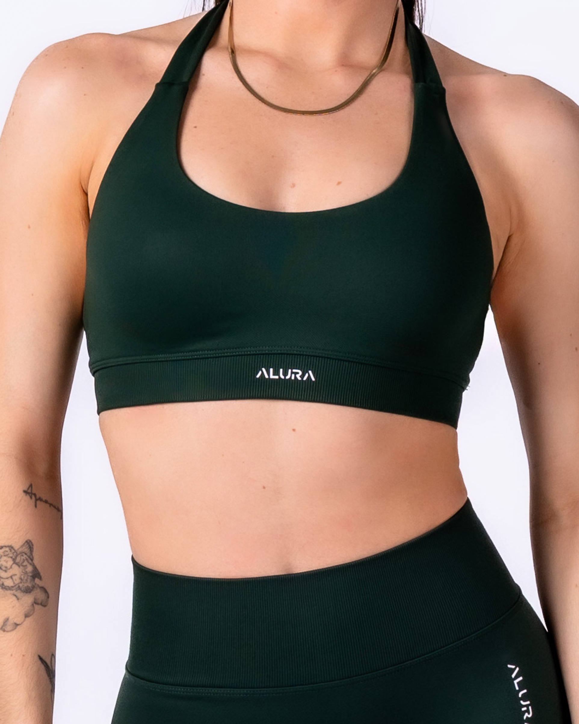 Person wearing a green sports bra with 'ALURA' branding on a white background
