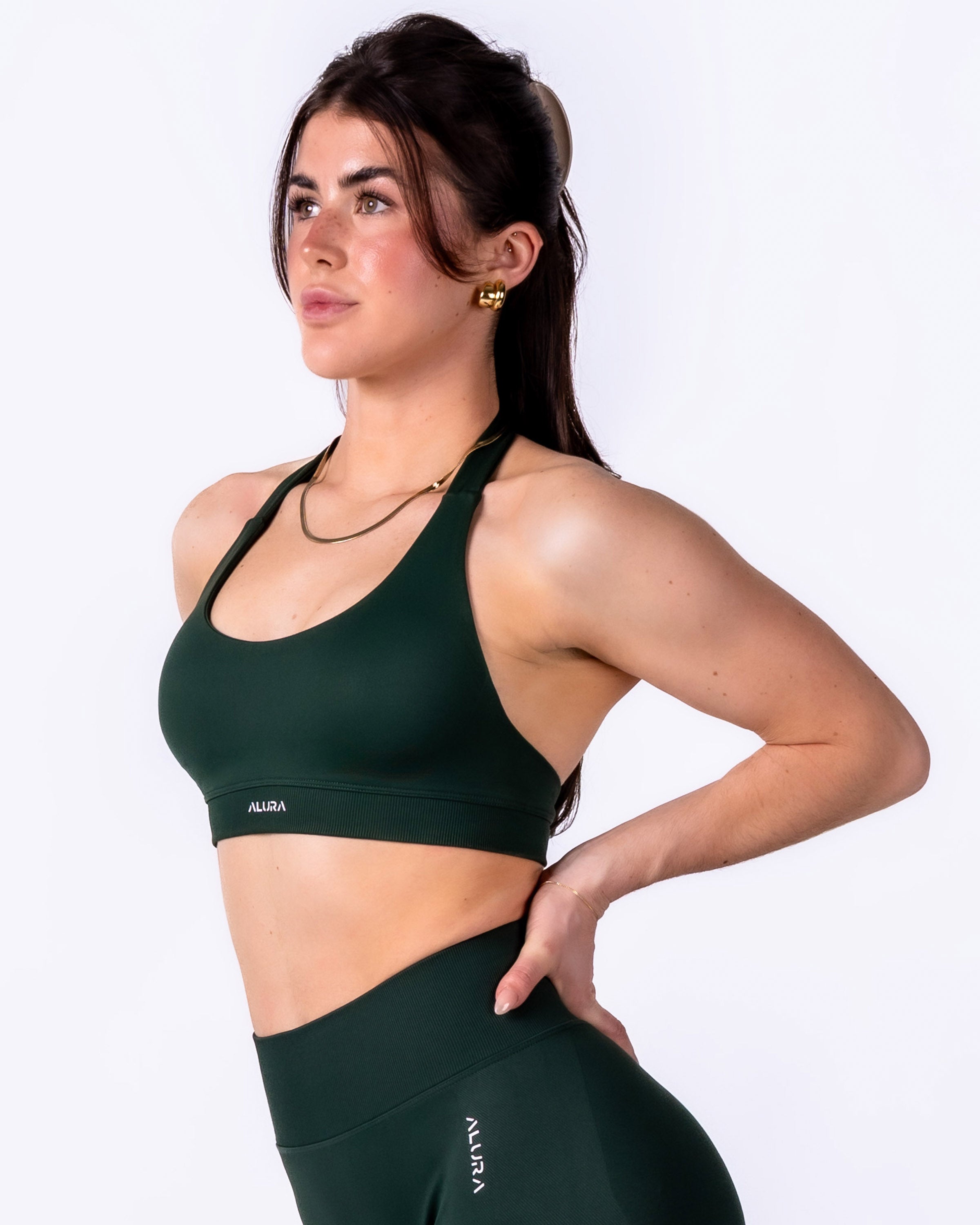 Woman wearing a green sports bra and leggings with 'Alila' branding on a white background
